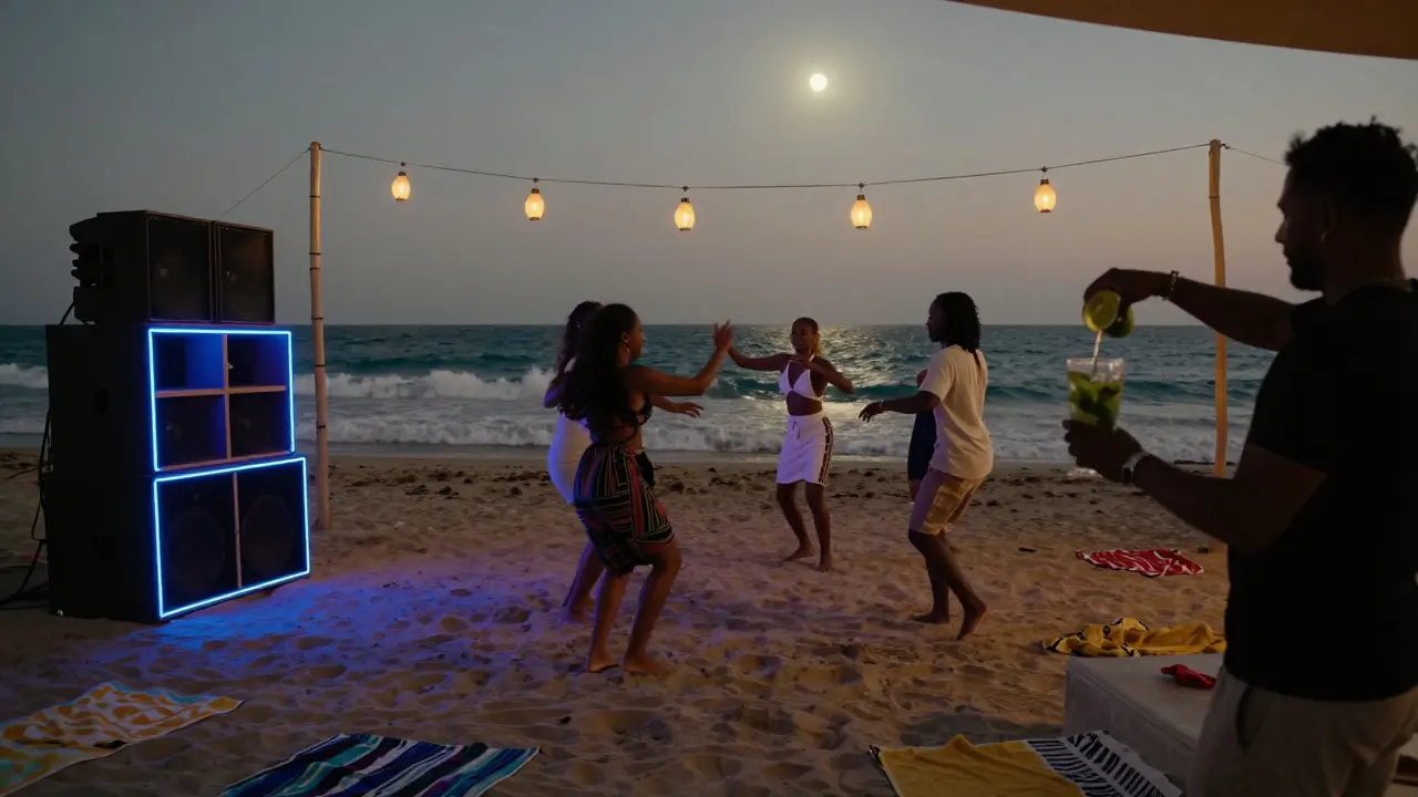Dancers barefoot on a beach at night, lanterns and speakers lit up as waves roll in behind them.